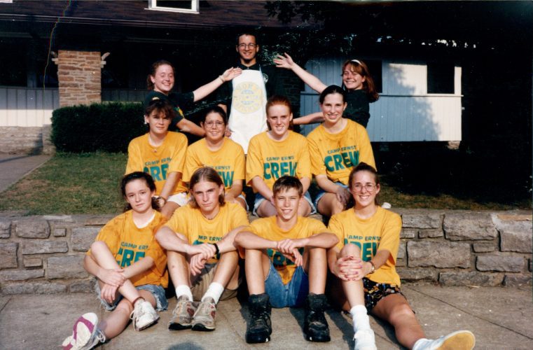 group of teens with yellow shirts sitting in front of standing adult leaders in dark green polos